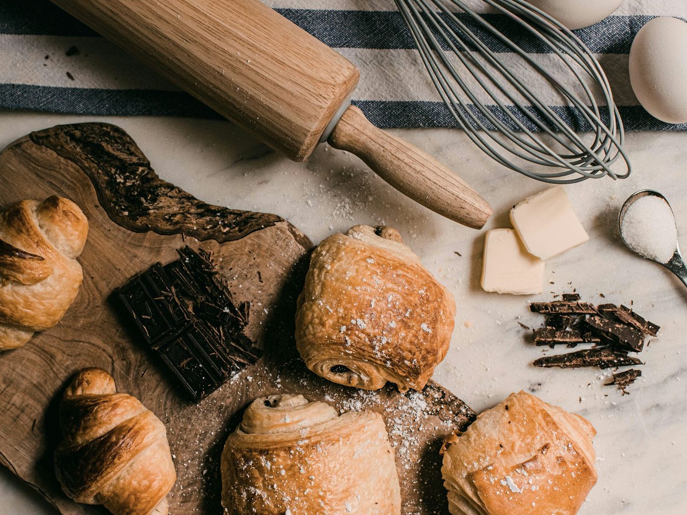 Pastries on a board with a rolling pin and whisk