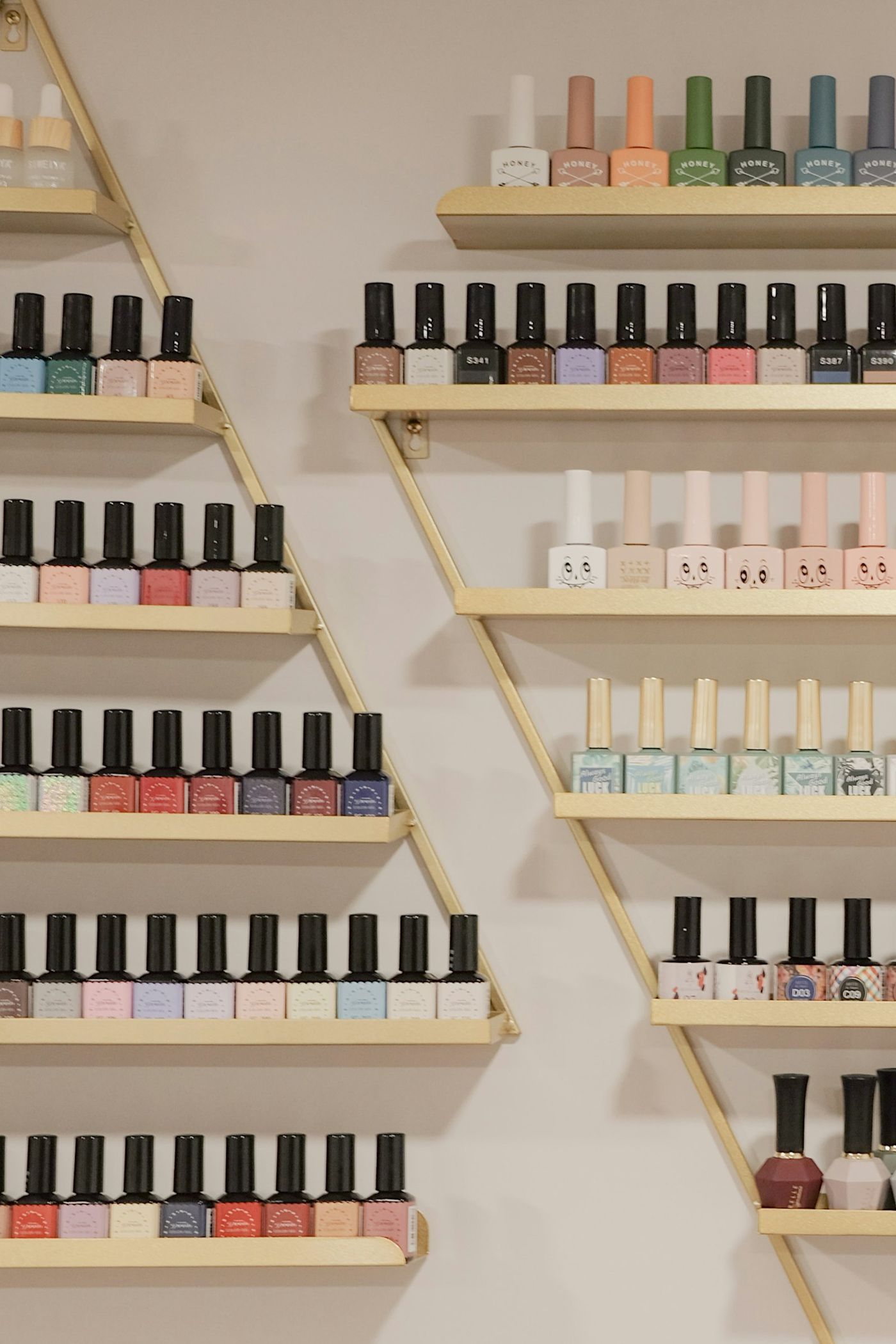Rows of nail polish bottles on gold shelves