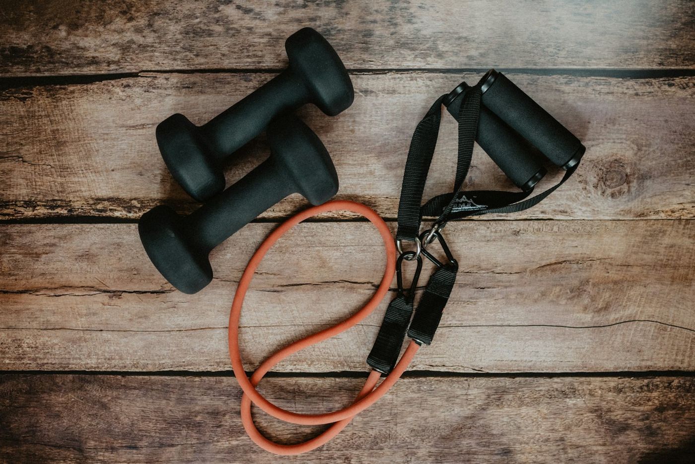 A resistance band and dumbbells on a wooden floor